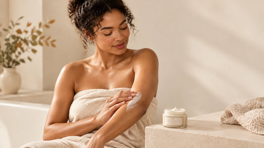 Adult woman applying body lotion in a calm, softly lit bathroom with Bathphoria Vanilla Oatmeal Lotion nearby